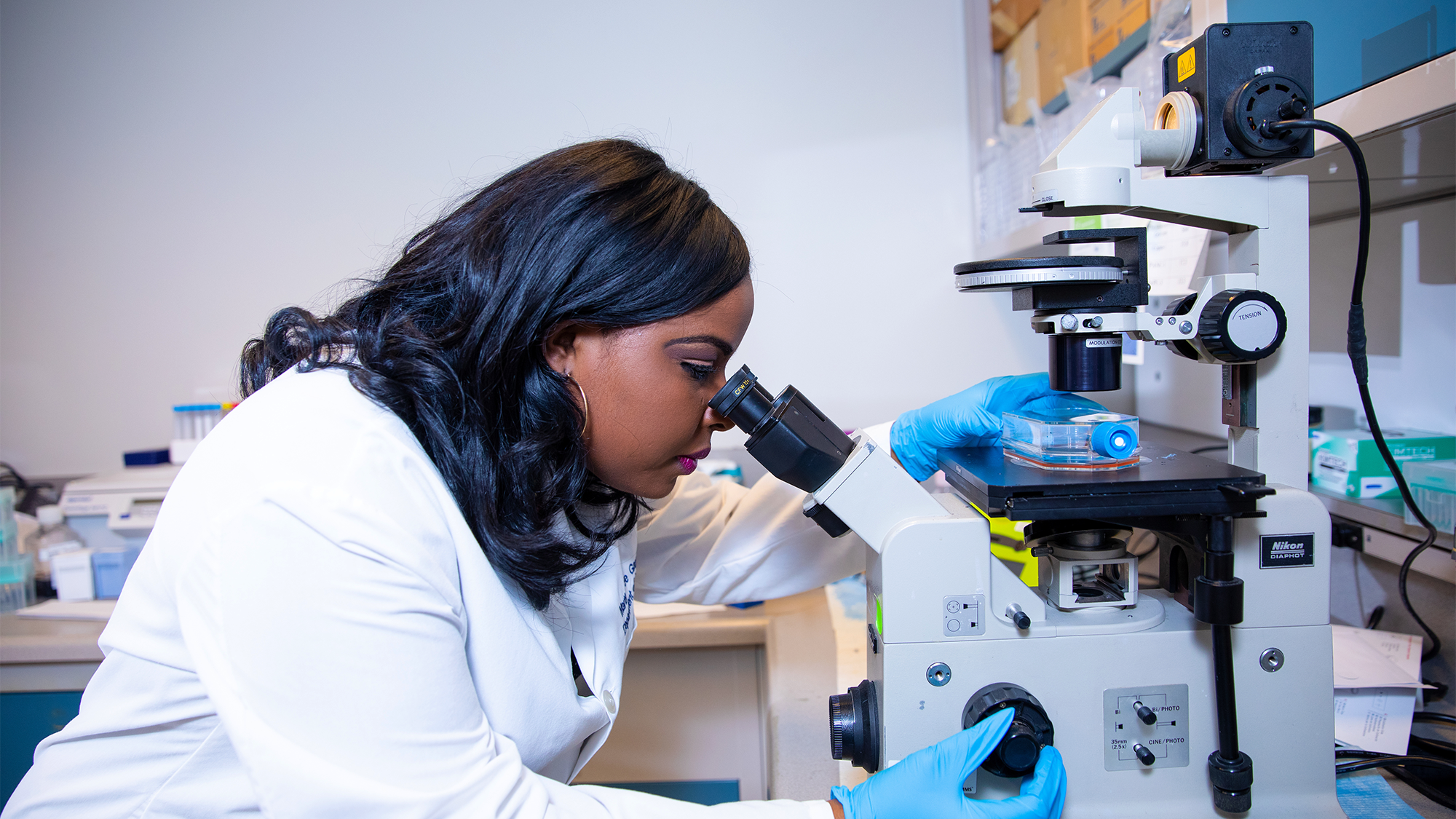 Dr. Gay looks through a microscope in a lab