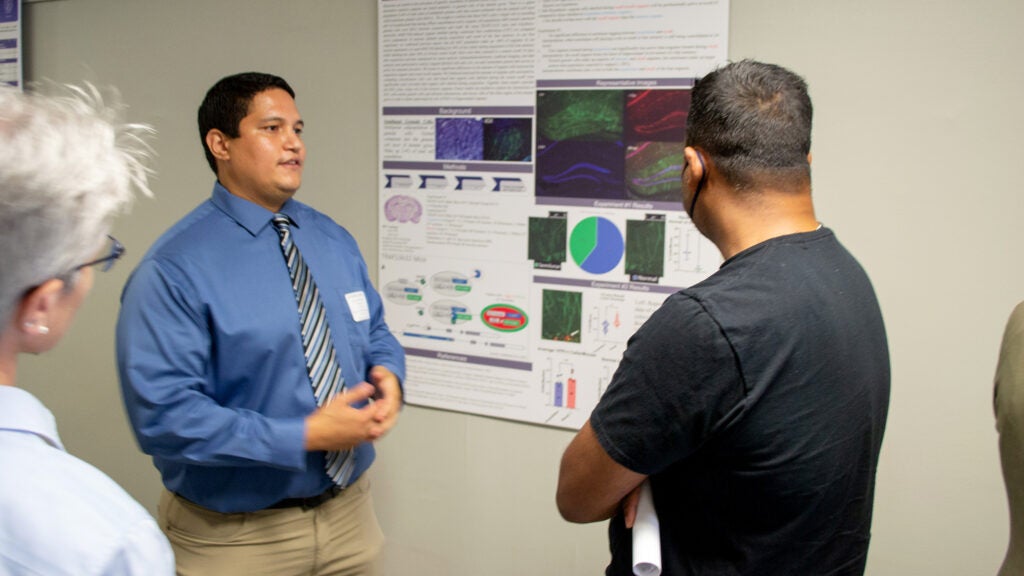 A student explains his poster presentation to an attendee