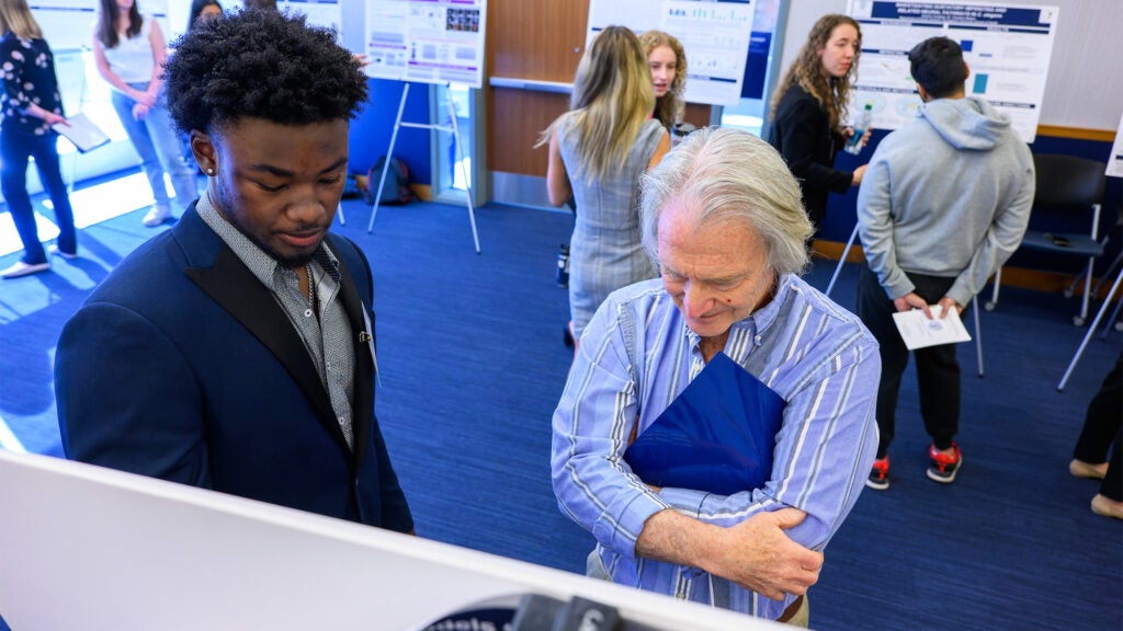 A student speaks with a professor about his poster at the Undergraduate Research Conference