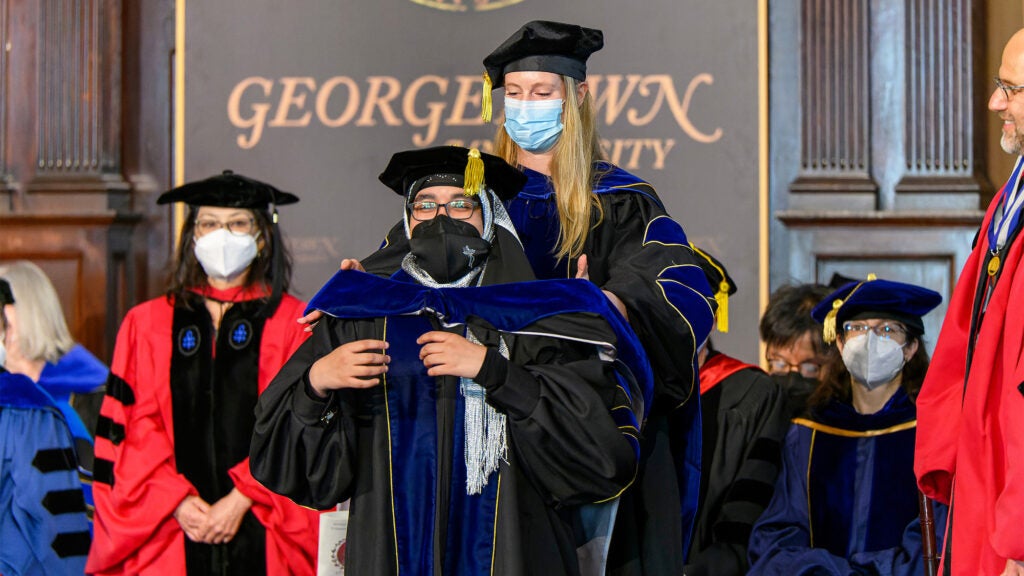 An MD/PhD student hoods a graduating PhD student