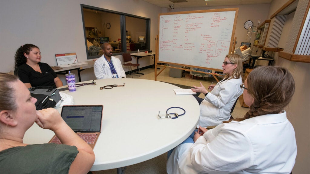 Nursing students discuss their work around a table